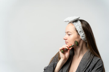 Woman massaging face with green jade roller © lorenzophotoprojects