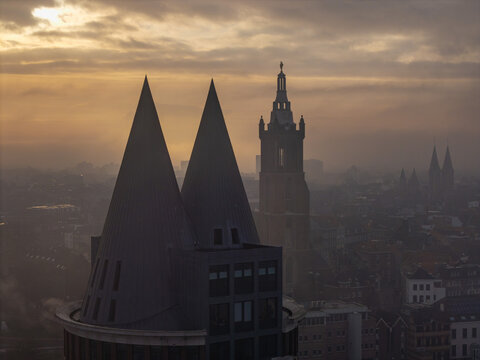 Aerial view of the skyline of Roermond, featuring the St. Christopher Cathedral tower and the Natalini tower with conical roofs during a misty sunset in Roermond, Limburg, Netherlands.