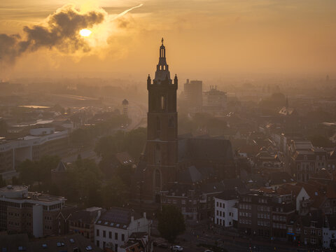 Aerial view of St. Christopher Cathedral surrounded by historic rooftops and urban streets during a golden sunset in Roermond, Limburg, Netherlands.