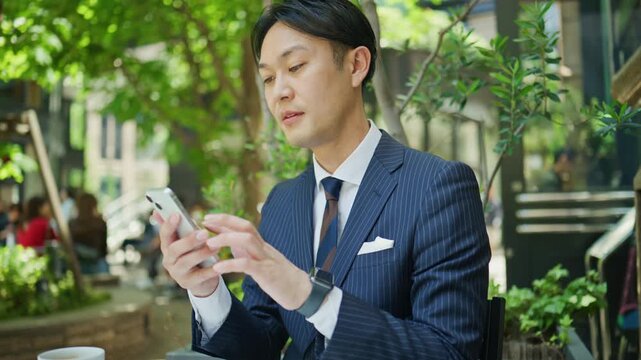 Japanese businessman checking his smartphone during a coffee break