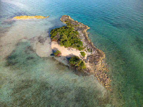Aerial view of a small tropical island with lush vegetation, sandy shores, and rocky outcrops near Coral Harbour Beach, Nassau, New Providence, The Bahamas.
