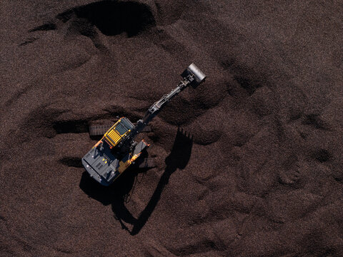 Aerial view of an excavator working on a large pile of coal in Gdansk, Poland.