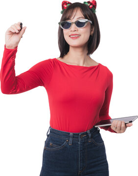 Happy smiling asian woman writing holding pen tablet wearing sunglasses reindeer headband red shirt celebrating christmas sale isolated on transparency background copy space