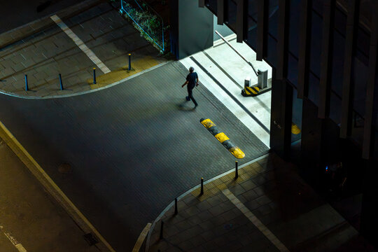 Aerial view of a security guard walking near the entrance of an underground garage at night.