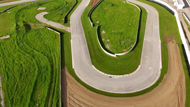 Aerial drone view of a hairpin bend on an empty motorsport circuit with gravel trap and tyre barriers