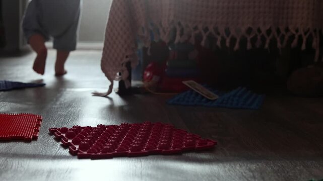 Toddler walking barefoot on orthopedic sensory mats for flat foot prevention at home