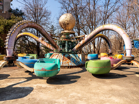 View of the rusted octopus amusement ride with colorful seats at the abandoned Yongma Land theme park in Seoul, Seoul, South Korea.