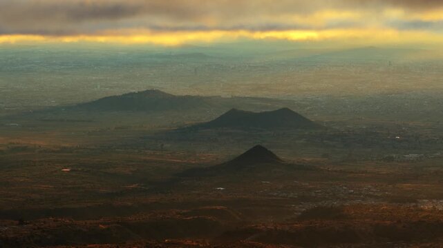 Volcanic hills and valleys near Popocatepetl in Izta Popo Zoquiapan National Park, Mexico, beneath a glowing cloudy sky. Cholula Valley, Puebla.