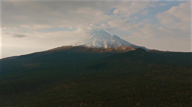 Popocatepetl volcano's snow covered summit above vast forested highlands in Izta Popo Zoquiapan National Park, Mexico. Smooth dolly in