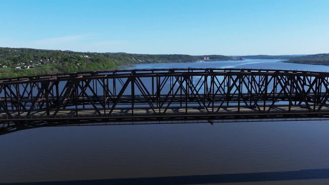Newburgh-Beacon Bridge truss spans the Hudson River against wooded New York hills, aerial orbit establishing