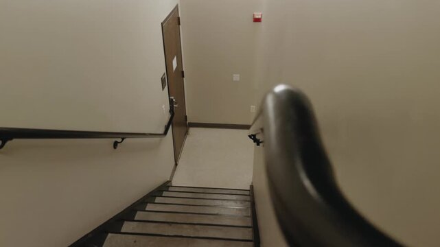 Left-to-right glide past black handrails and stairs inside an empty stairwell.