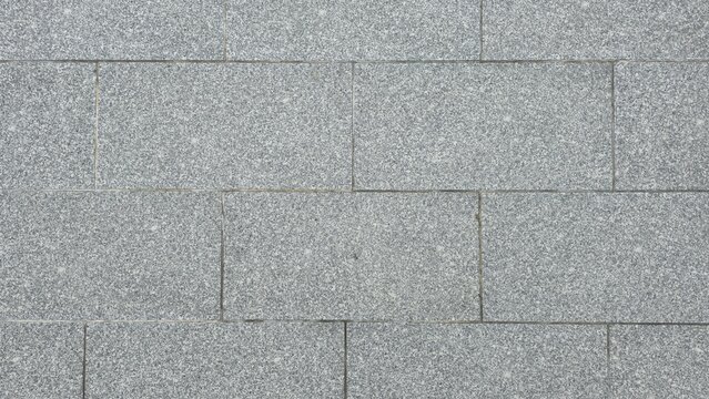 Abstract grey granite paving stone floor texture surface. Grey granite stone blocks floor texture background. Top view pattern of rectangular grey granite tiles on outdoor sidewalk pavement.
