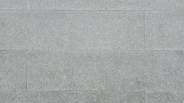 Abstract grey granite paving stone floor texture surface. Grey granite stone blocks floor texture background. Top view pattern of rectangular grey granite tiles on outdoor sidewalk pavement.