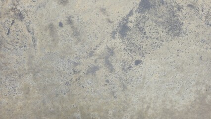 Fototapeta premium Old beige-grey concrete texture with raw dark stains. Grunge earth tone cement texture background. Close-up of weathered cement surface showing rustic mottled patterns.The old cement floor has marks.