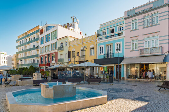 View of a charming town square featuring a central fountain, colorful historic buildings, and cobblestone pavement in Lagos, Faro District, Portugal.