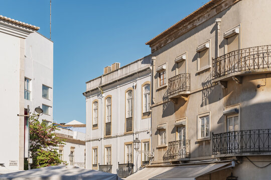 View of historic buildings with traditional balconies and white facades under a clear blue sky in the old town of Lagos, Faro District, Portugal.