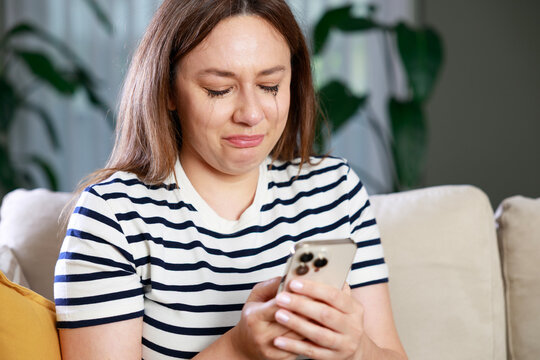 Heartbroken woman crying while looking at smartphone