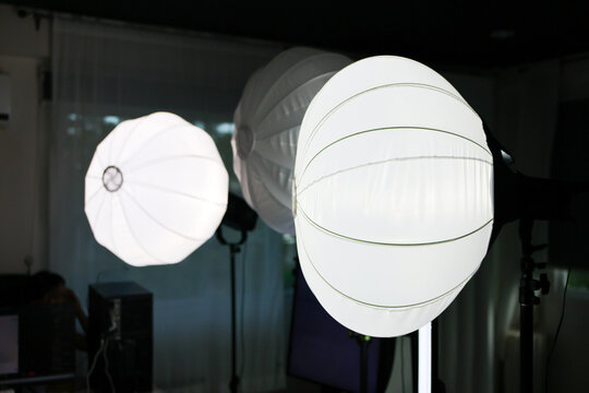 Studio lighting equipment with white spherical softbox, umbrella diffuser, and photographic workspace creating professional illumination setup