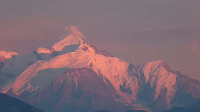 View of Mont Blanc mountain range illuminated by the warm light of sunset with snow-capped peaks and glaciers in Chamonix, Auvergne-Rhone-Alpes, France.