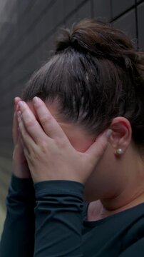 Weeping young female seated on corridor floor hiding face in open palms experiencing cathartic tears grief release and deep psychological surrender