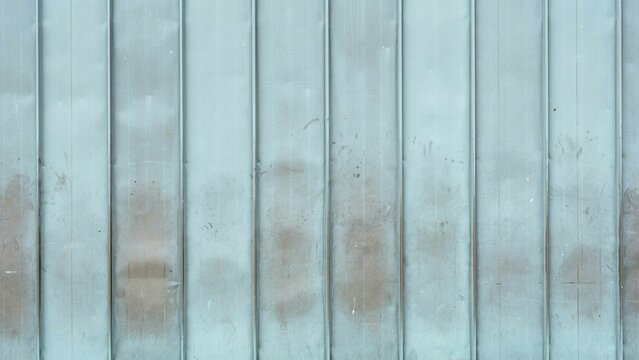 Weathered corrugated metal texture, industrial blue steel wall background with rust stains. Grungy metallic fence surface, aged iron paneling for architectural design.