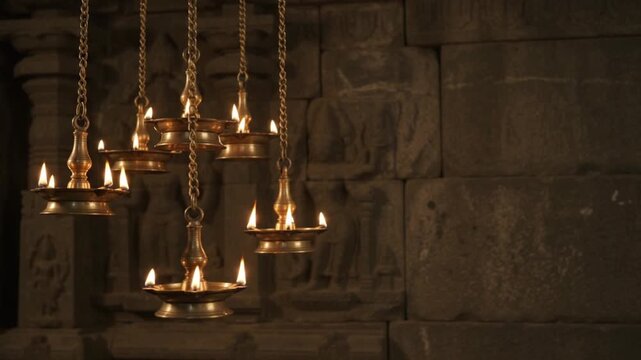 Traditional Hanging Brass Diya Lamps with Burning Flames Inside Ancient Indian Stone Temple for Diwali Celebration