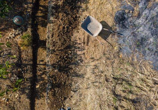 Aerial View of a Traditional Farm Cart in an After-Harvest Rice Field with Rice Straw Ash. The Rural Agricultural Scene Highlights Post-Harvest Farming Practices and Field Management Viewed from Above