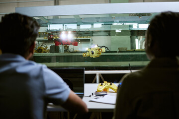 Multiethnic young students testing underwater robotic drone in water tank during engineering...