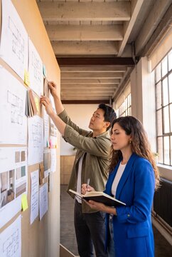Interior designers reviewing fabric swatches and floor plans on a corkboard