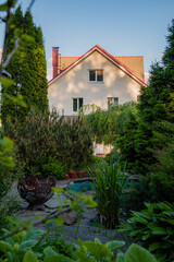 Obraz premium Charming garden view showcasing a cozy house surrounded by lush greenery
