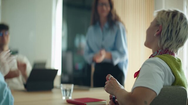 Woman receives applause from coworkers during a business meeting in the office, highlighting recognition, teamwork, support, leadership, and positive workplace communication around a conference table.