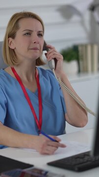 Female nurse talking on the telephone at the hospital reception