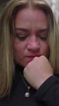 Anxious adult female pressing clenched knuckles to mouth in domestic passageway enduring acute hesitation suppressed panic and painful self interrogation