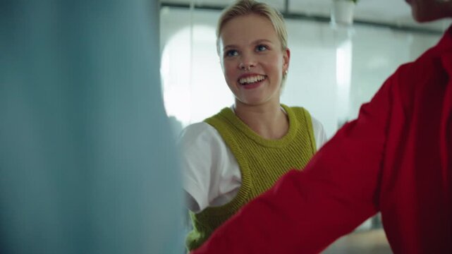 Team raises hands with coworkers in the office to mark success through a huddle and shared cheer, expressing collaboration, unity, support, motivation, and workplace culture.