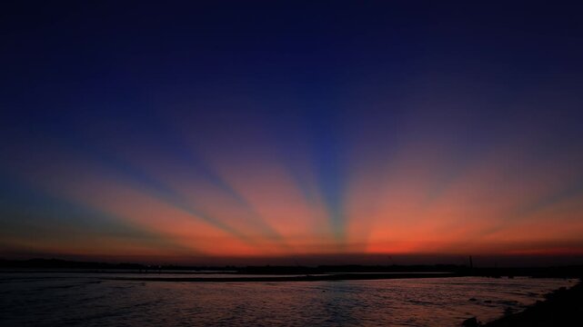 Dramatic Sunset Sky with Sunbeams Over Calm Ocean Horizon