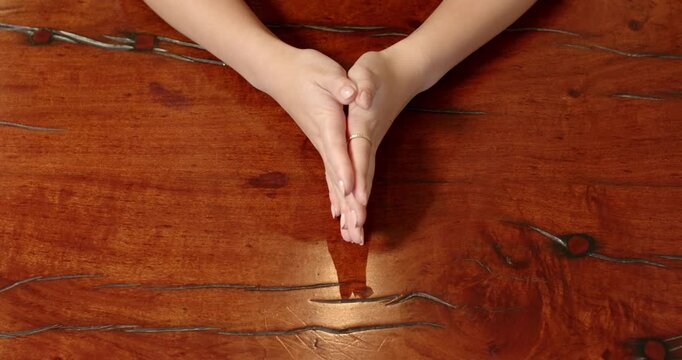 Close up of people talking to the camera, hands on wooden table