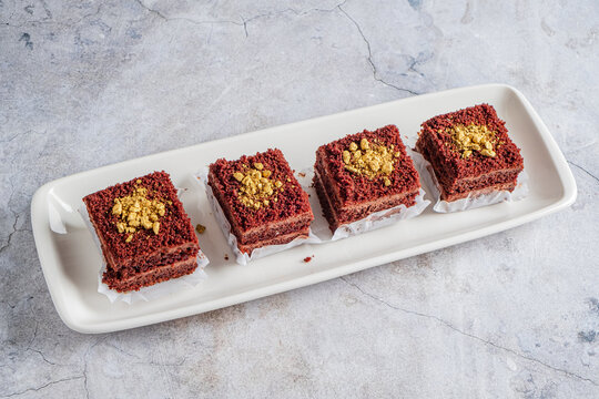 Delicious red velvet cake squares topped with crunchy nuts on a sleek platter