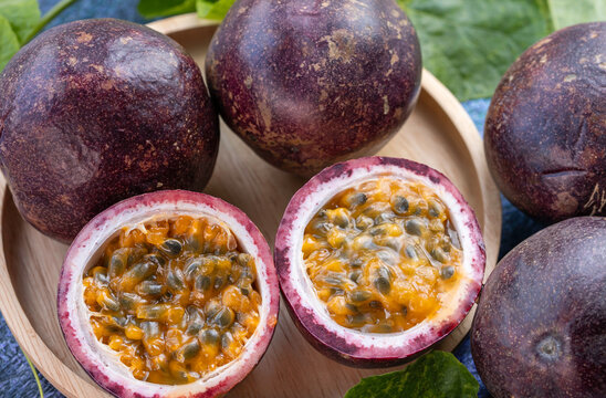Fresh Passion fruit in wooden plate, Purple Passion fruit or Maracuya with leaf on a wooden table.