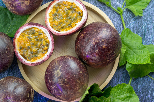 Fresh Passion fruit in wooden plate, Purple Passion fruit or Maracuya with leaf on a wooden table.