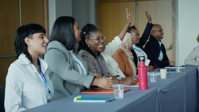 Engaged diverse group raises hands, showing participation and enthusiasm during a productive conference or business meeting. Positive and collaborative atmosphere.
