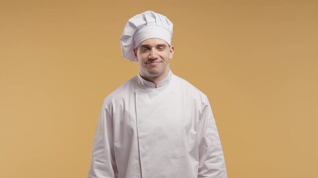 Smiling professional male chef nodding yes in approval, handsome cook in white uniform and toque showing agreement, satisfaction and positive reaction