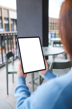Vertical mockup image of a woman holding digital tablet with blank white desktop screen in cafe