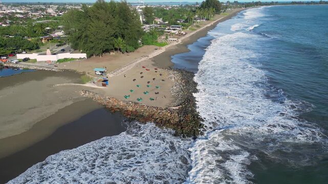 Meulaboh, Indonesia : Slow motion tilt up aerial drone footage of wave breaks into beach by small stalls in Meulaboh, coastal town in Aceh province of Sumatra in Indonesia.