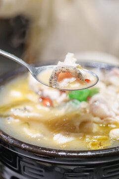 Woman tourist eating Sichuan Fish with Pickled Mustard Greens or Suan Cai Yu in restaurant. Popular foods for tourist eating in Chengdu, Chongqing and China. Chinese Asia and Sichuan foods concept