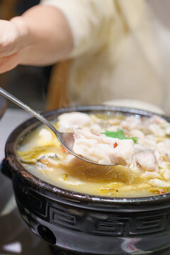 Woman tourist eating Sichuan Fish with Pickled Mustard Greens or Suan Cai Yu in restaurant. Popular foods for tourist eating in Chengdu, Chongqing and China. Chinese Asia and Sichuan foods concept