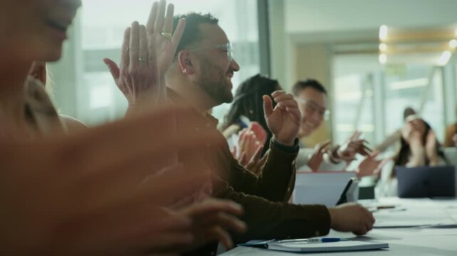 Group of business professionals enthusiastically clapping and laughing at a successful meeting. Their joyous reaction indicates a positive outcome or achievement during a conference or seminar.