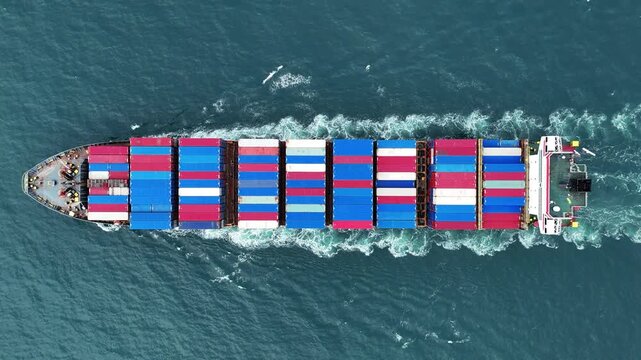Aerial top view of cargo ship with contrail in the ocean sea ship carrying container and running from container international port smart freight shipping by ship service