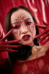 Naklejka premium Young Asian woman embodies dark royalty with bloody vampire allure for Halloween