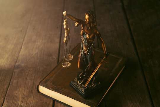 Justice Scales, Law books and Lady Justice on wooden table.