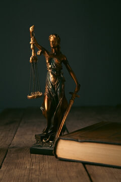 Justice Scales, Law books and Lady Justice on wooden table.